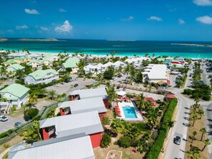 Luchtbeeld van een resort met meerdere gebouwen, een zwembad en een strand.