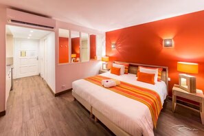 Een hotelkamer met een groot bed, een spiegel, een nachtkastje en een wandlamp.