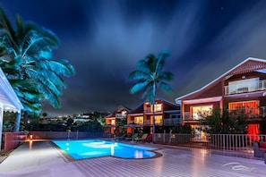 Een resort met een zwembad, meerlaagsgebouwen en palmbomen.