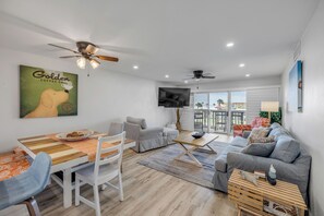 Ein modernes Wohnzimmer mit Essbereich, einem an der Wand montierten Fernseher und einem Balkon mit Blick.