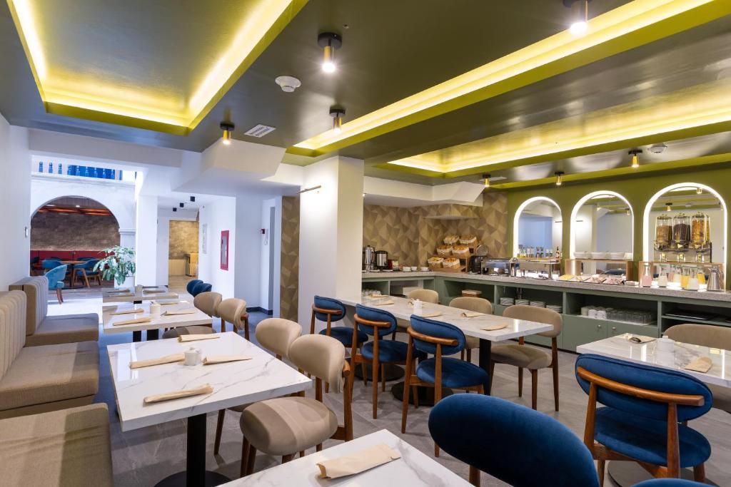 Un restaurant doté de plusieurs tables et chaises, d’un bar et d’un espace détente avec des canapés.