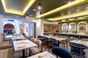 Un restaurant doté de plusieurs tables et chaises, d’un bar et d’un espace détente avec des canapés.