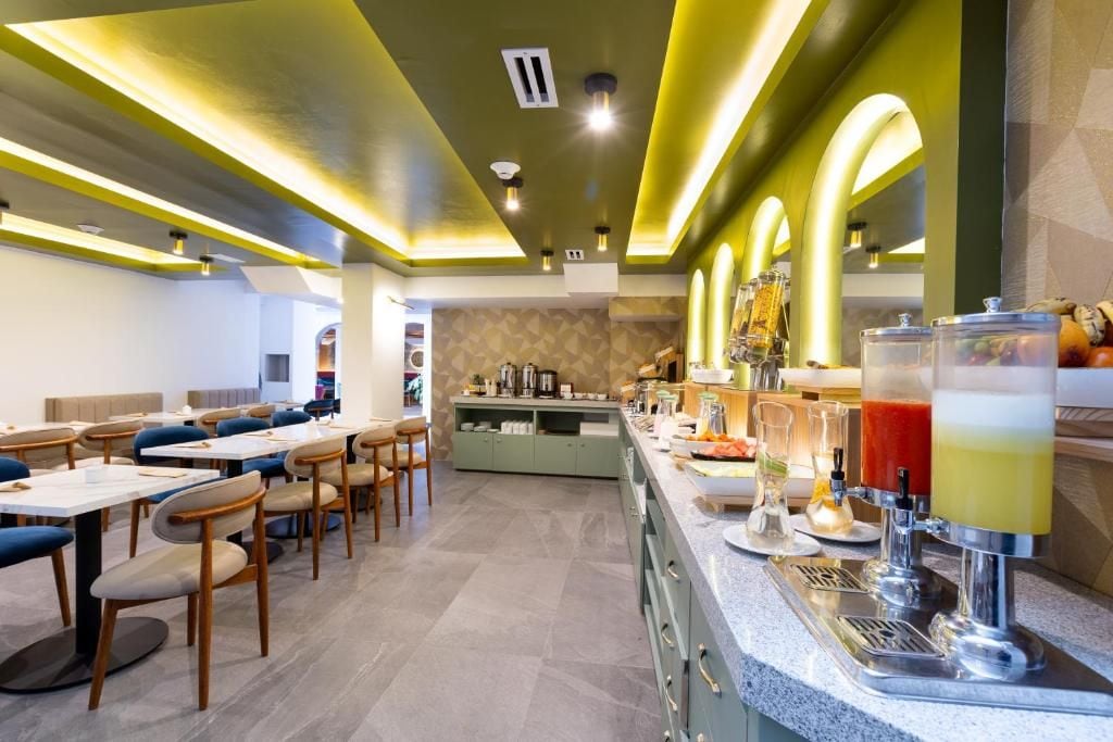 A restaurant with tables and chairs, a bar area with a drink dispenser, and a counter with food items.