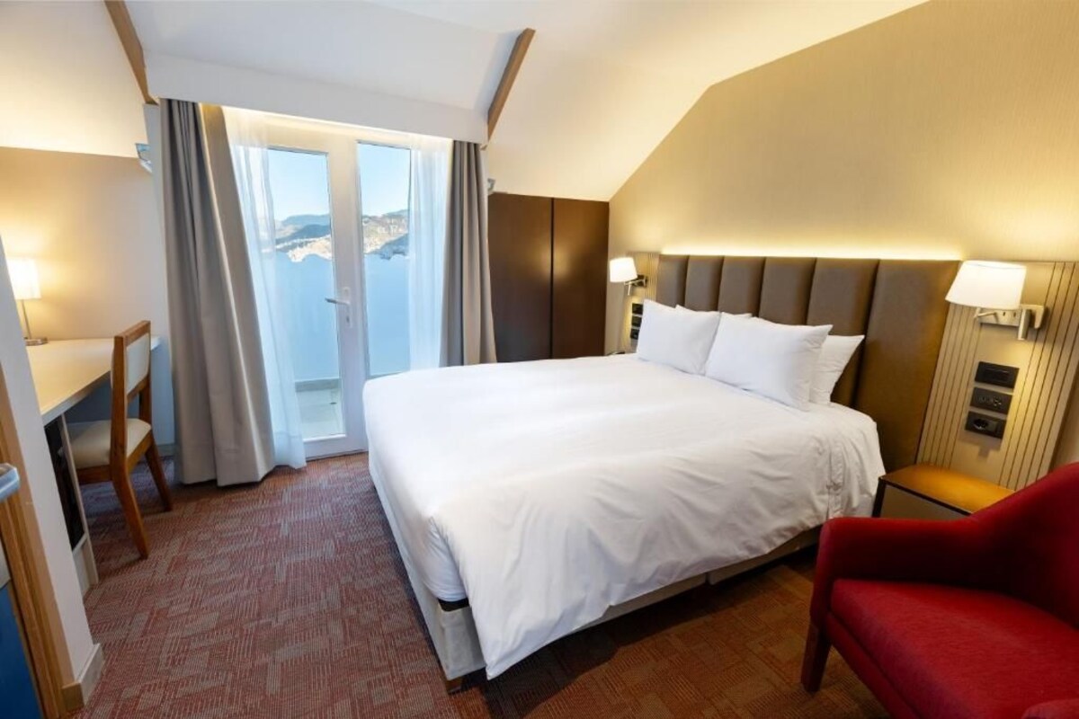 Une chambre d’hôtel avec un grand lit, un bureau, une chaise et une vue sur la mer.
