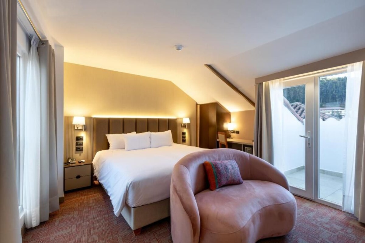 Une chambre d’hôtel dotée d’un grand lit, d’un coin salon et offrant une vue sur l’extérieur.