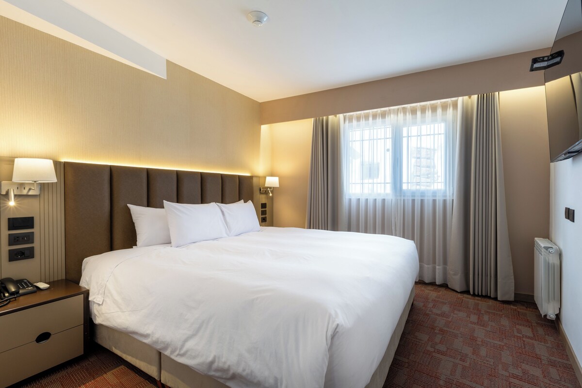 Une chambre d’hôtel avec un grand lit, des lampes de chevet, un téléphone et un radiateur.