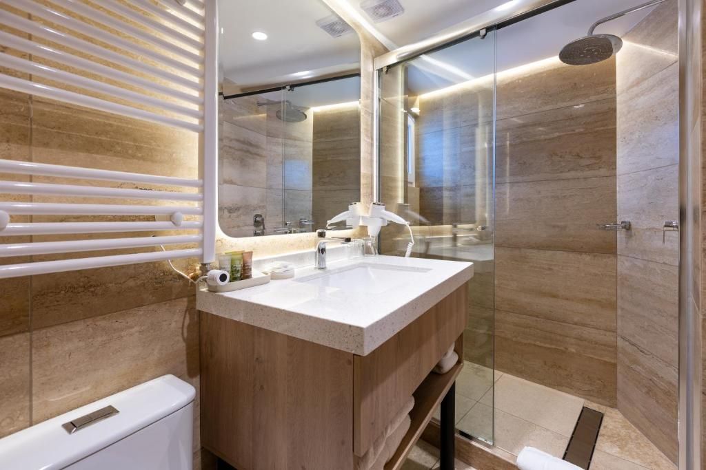 Une salle de bain moderne avec un meuble-lavabo en bois, une cabine de douche en verre et un grand miroir.