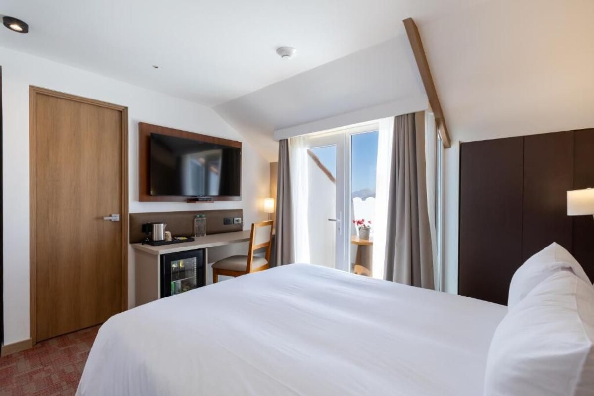 Une chambre d’hôtel comprenant un lit, un bureau avec une télévision, un minibar et une vue sur l’extérieur.
