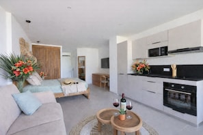 Een modern appartement met kitchenette, een bed met uitzicht, een eethoek en een woonkamer met een bank en salontafel.
