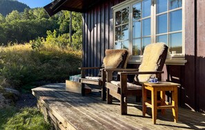 A wooden deck with two chairs and a small table, overlooking a forested area. - Gorgeous home in Passebekk with house a panoramic view (Passebekk)