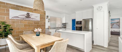 A modern kitchen with white cabinets, a built-in oven, and a refrigerator.