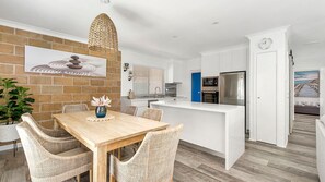 A modern kitchen with white cabinets, a built-in oven, and a refrigerator. - Easy walker Luxe Villa Walking Distance to Town (Crescent Head)
