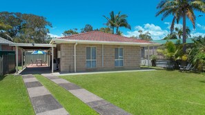 A two-story house with a red-tiled roof, a covered patio, and a well-maintained lawn. - Easy walker Luxe Villa Walking Distance to Town (Crescent Head)