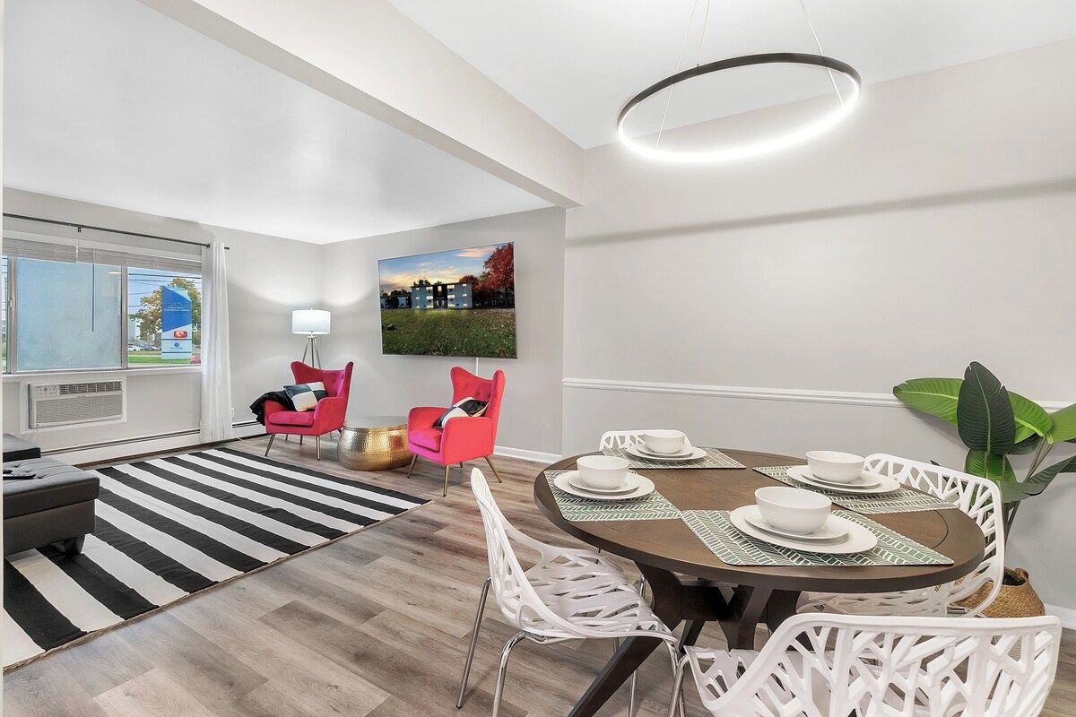 A modern dining area with a round table, white chairs, and a black and white striped rug.
