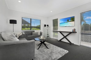 A modern living room with a grey sofa, a coffee table, and a TV mounted on the wall.