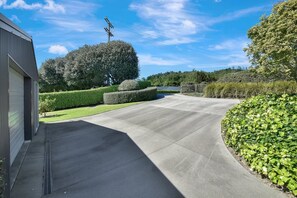 A residential driveway with a garage, neatly trimmed hedges, and a clear sky.