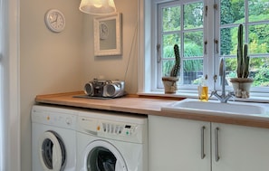 A kitchen with a washing machine, a radio, and a window with cacti. - Stunning home in Herning with WiFi (Herning)