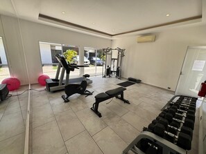 A gym with exercise equipment, a bench, and dumbbells. - CARIBBEAN CORNER (Cancún)