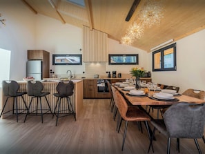 Eine moderne Küche mit Essbereich, Holzboden und integrierten Fernsehern.