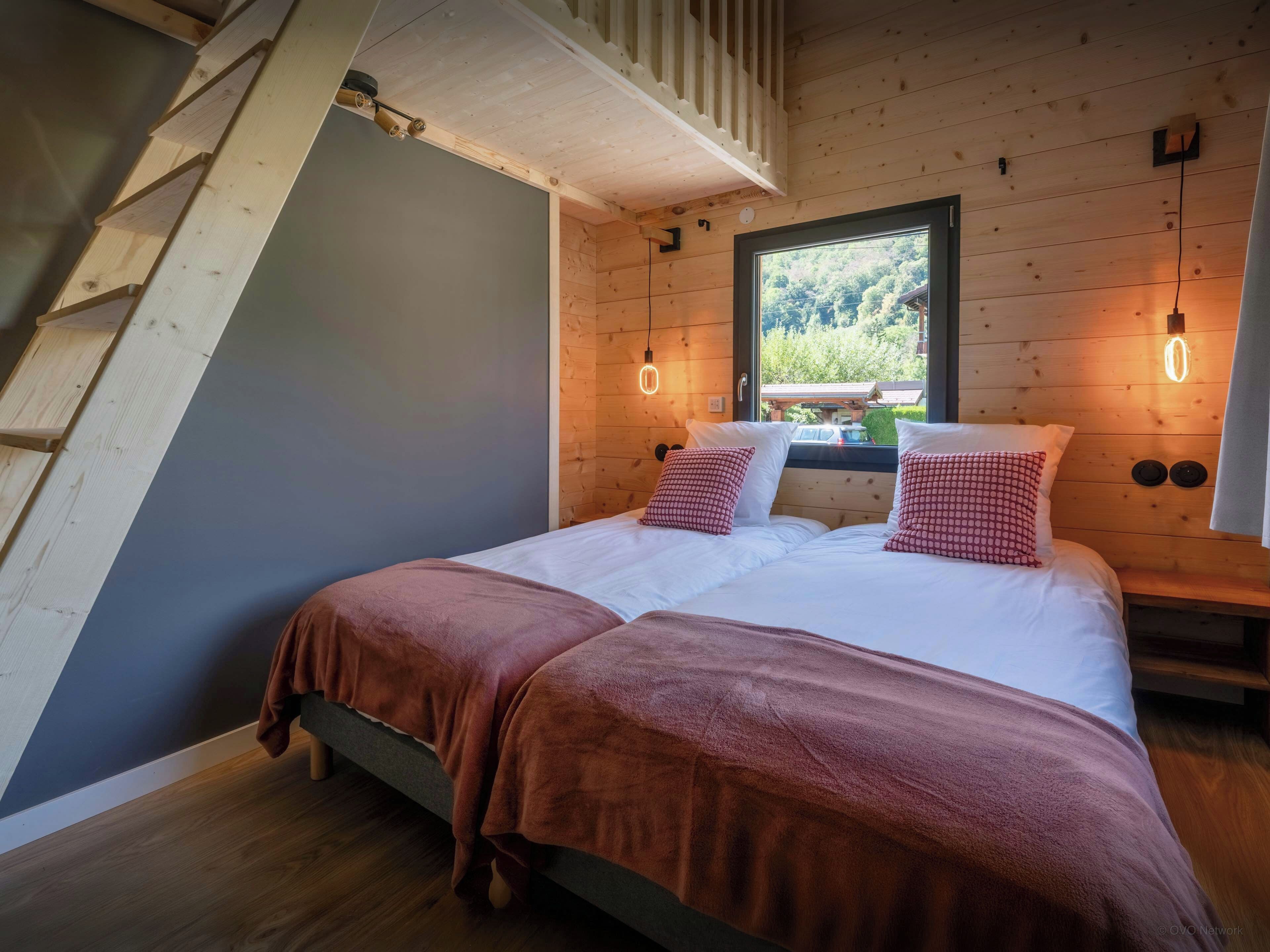 Une chambre à coucher avec un lit, des murs en bois, une fenêtre et une échelle en bois.