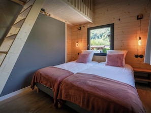 Ein Schlafzimmer mit einem Bett, Holzwänden, einem Fenster und einer Holzleiter.