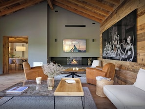 Un ampio soggiorno con camino, posti a sedere confortevoli e una grande TV a parete.