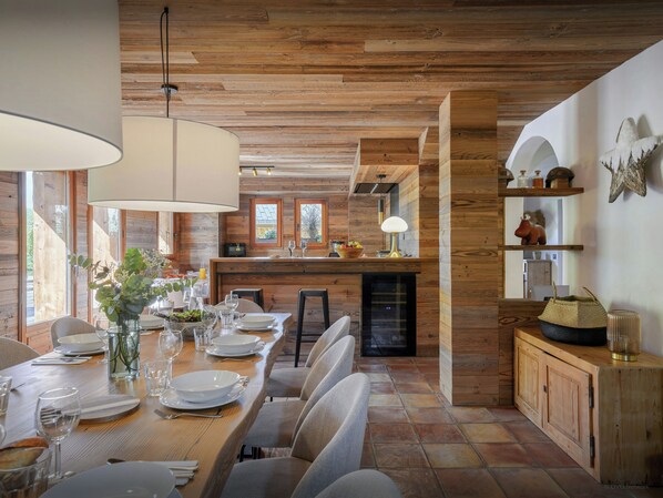 Un interno in legno con un tavolo da pranzo per quattro persone, angolo cottura e un'ampia finestra che lascia entrare molta luce naturale.