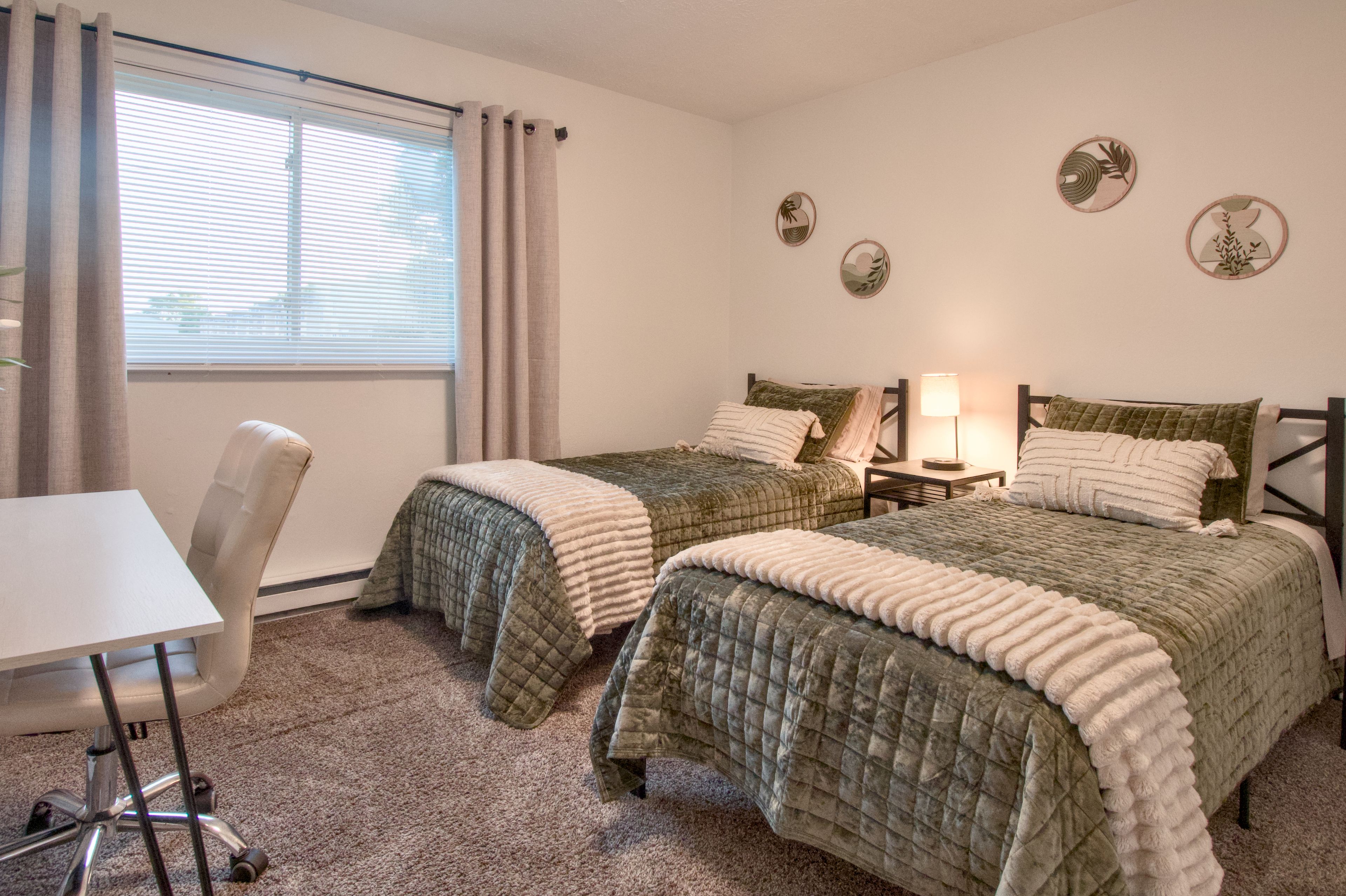 A hotel room with two beds, a desk, and a chair.
