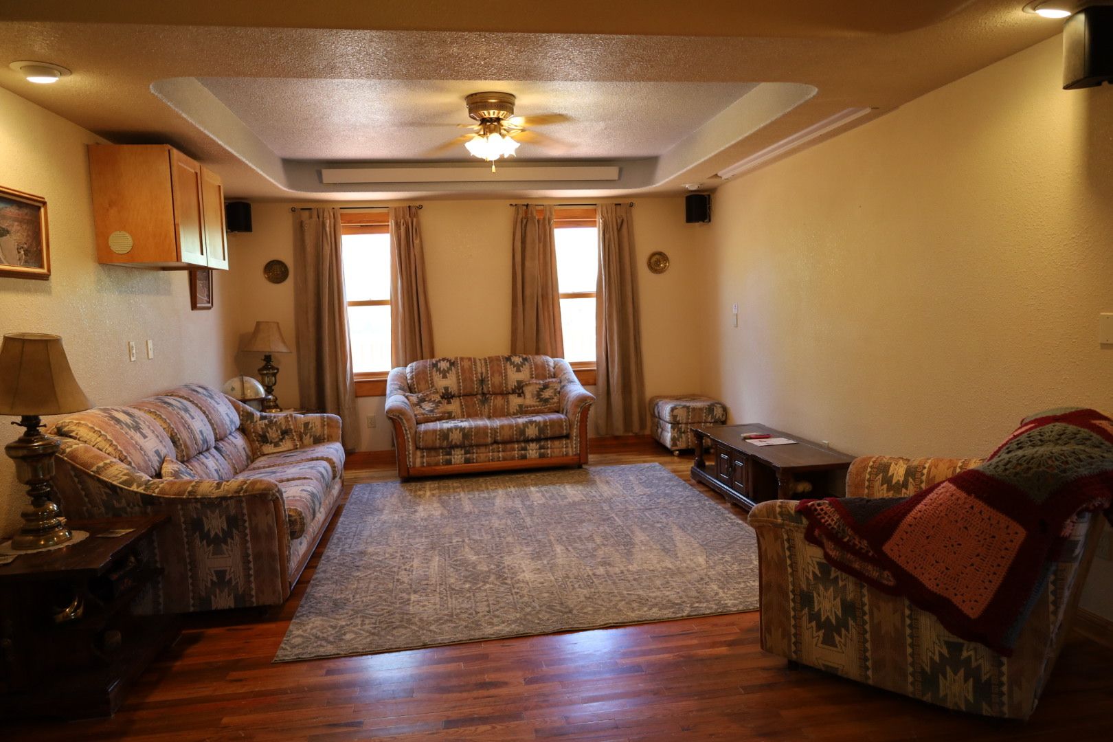A living room with a sofa set, a coffee table, a rug, and a ceiling fan.