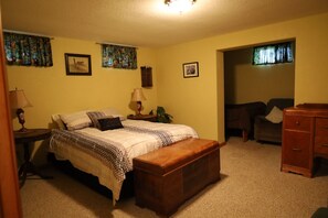 Un dormitorio con cama, mesitas de noche, cómoda y ventana con cortinas.
