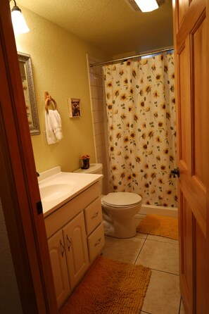 Un baño con inodoro, lavamanos y cortina de ducha con estampado de girasoles.