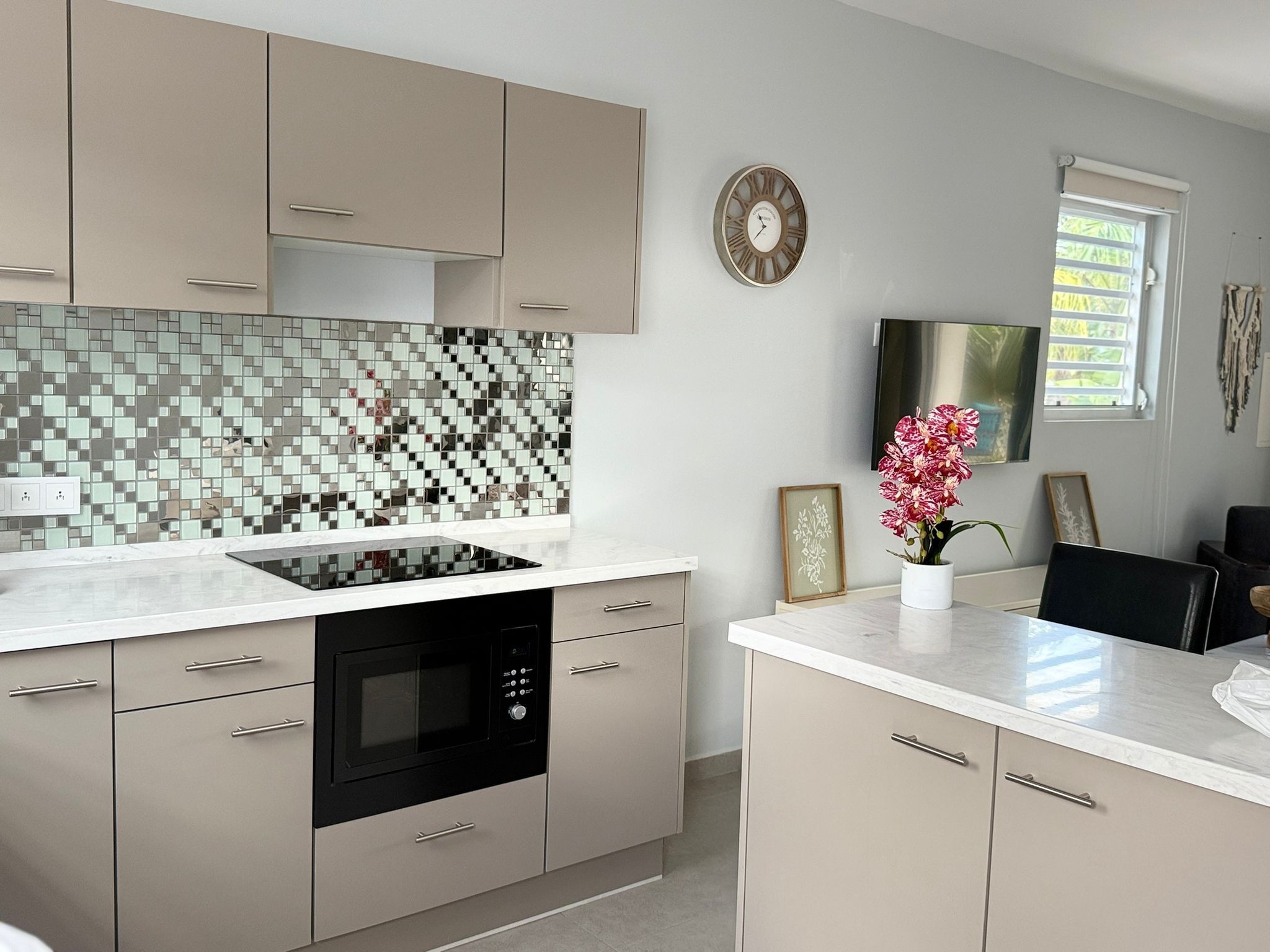 A modern kitchen with a tiled backsplash, built-in oven, and a dining area with a table and chairs.