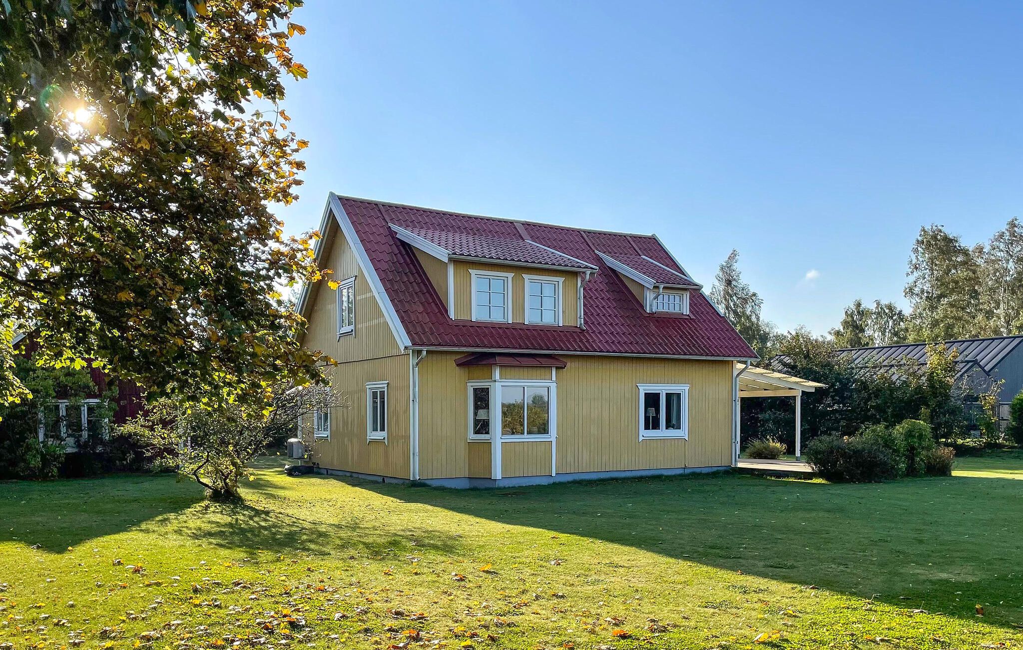 Une maison à deux étages avec un toit rouge, un revêtement de couleur beige et de nombreuses fenêtres.