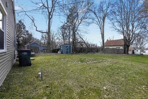 Ein Wohngrundstück mit Rasenfläche, Gartenhaus und Haus.
