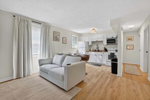 A modern apartment with a living room, kitchen, and dining area. - Pleasant on Pheasant 2BR I 1 BA (Lansing)