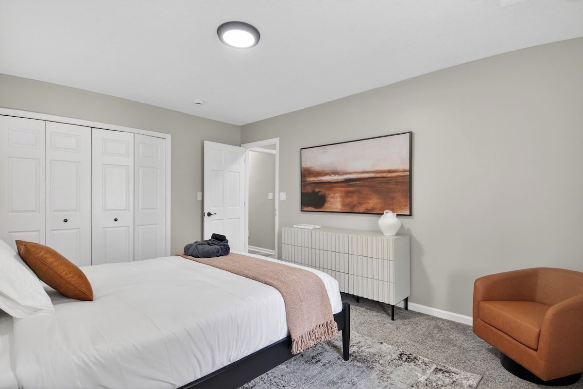 A bedroom with a bed, a chair, a radiator, and a door.