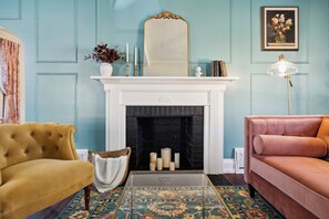 A room with a fireplace, a sofa, a chair, and a patterned rug. - Walk to Sparrow I 2 BR I 1 BA (Lansing)