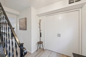 A staircase with a metal railing, a coat rack, and a white door with two handles. - Radiant Retreat 3BR / 2BA Home (Lansing)