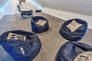 A room with four bean bags, a bed with pillows, and a wall with string lights. - Little Loft of Adventure | 1 Br 1 Ba (Lansing)