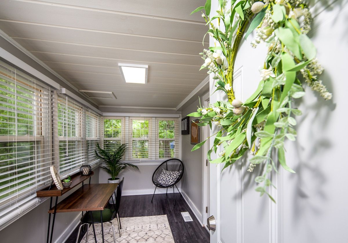 A room with a wooden table, a chair, a potted plant, and a decorative wall arrangement.