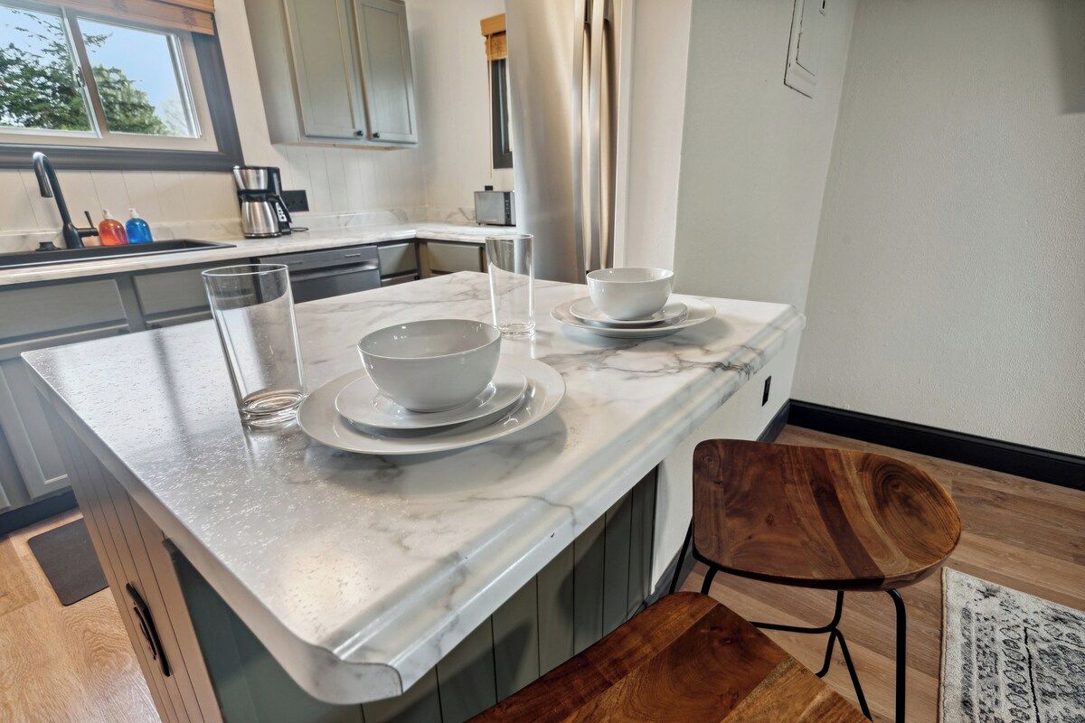 A kitchen island with a marble countertop, a coffee maker, and a window above the sink.