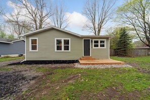 A single-story house with a front porch, a door, and a small window on the front. - 3BR/1BA w/Backyard & Firepit (Lansing)