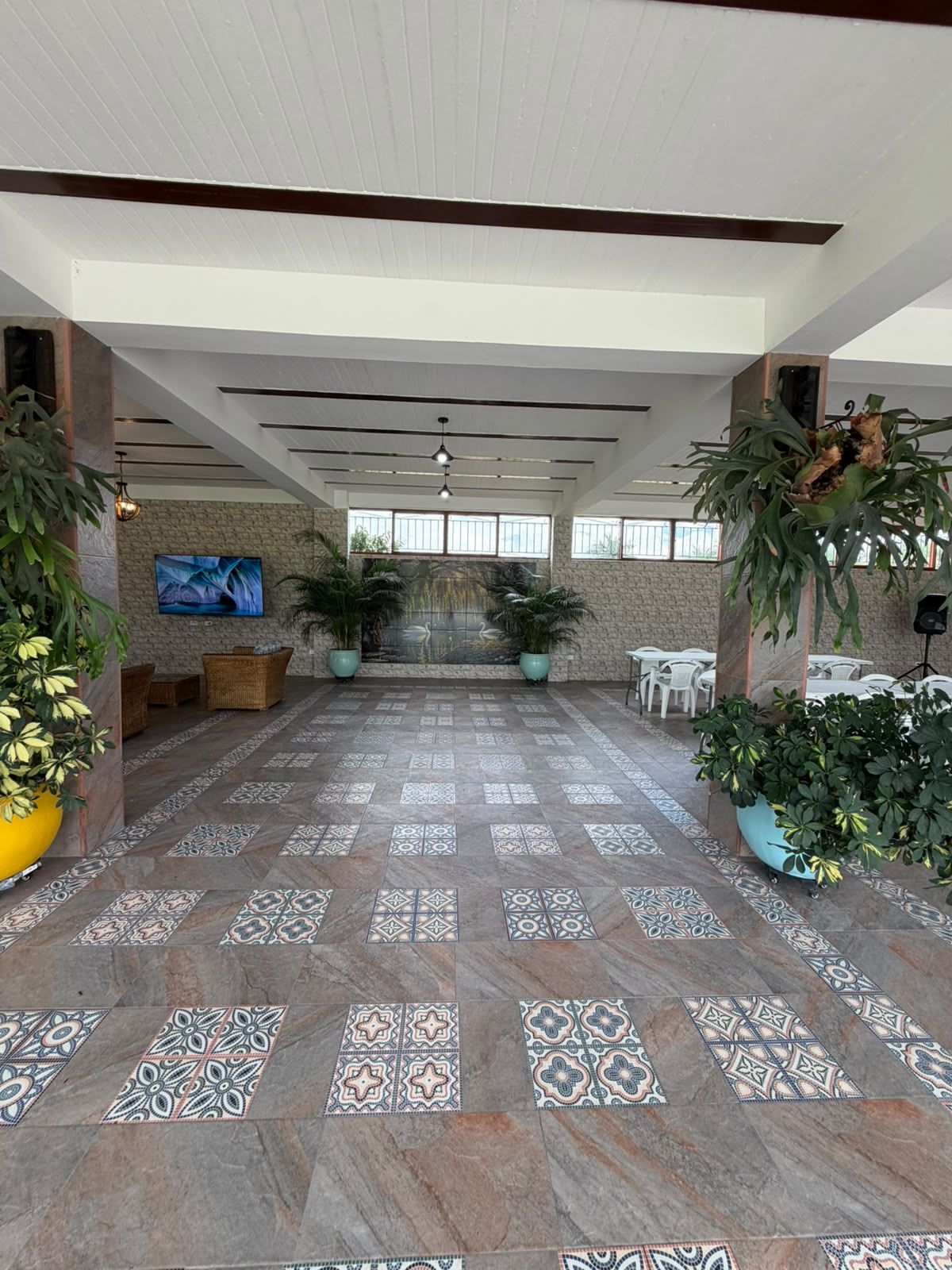 A spacious indoor area with patterned flooring, seating arrangements, and potted plants.
