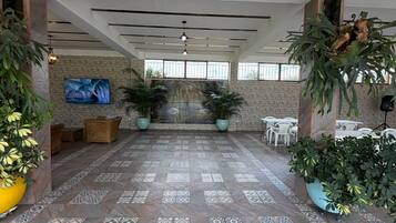 A spacious indoor area with patterned flooring, seating arrangements, and potted plants.