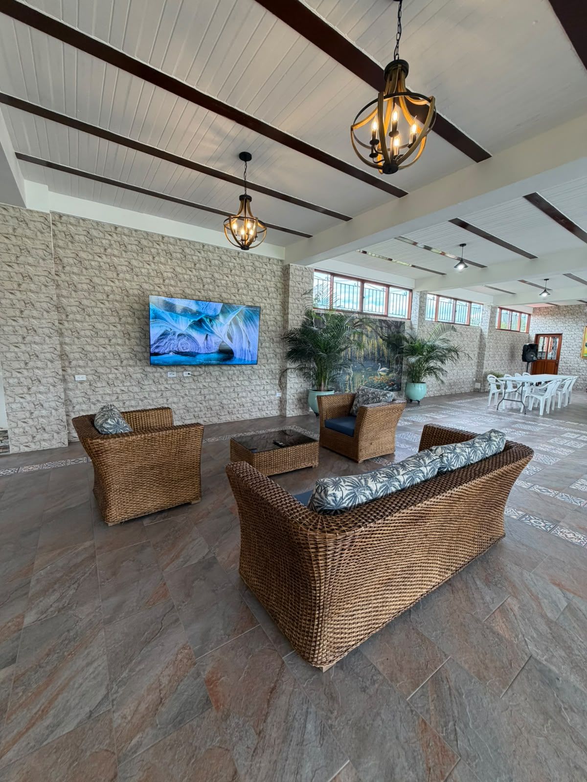 A spacious lobby with a stone wall, a large flat-screen TV, wicker furniture, and a ceiling fan.