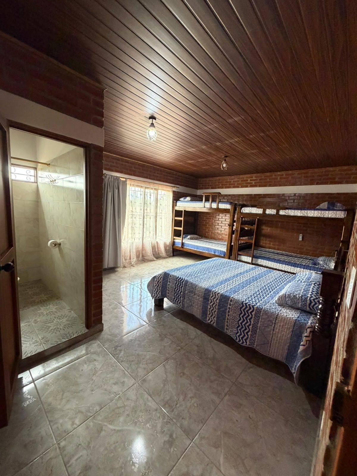 A room with a bunk bed, a shower area, and a door leading to another room.