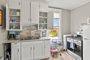 A modern kitchen with white cabinets, a built-in oven, and a view of the outside. - Spacious downtown getaway for the whole family! (Omaha)