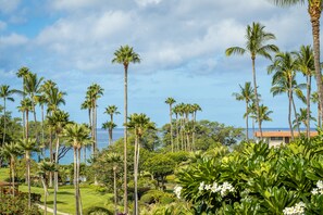 A tropical landscape with palm trees and a view of the ocean. - South Kihei condo with partial ocean view, pool, hot tub, and lanai (Kihei)