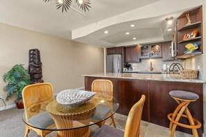 A modern kitchen with a central island, dark wooden cabinets, and a stainless steel refrigerator. - South Kihei 1BR condo with partial ocean view, pool, hot tub, and lanai (KS5311) (Kihei)