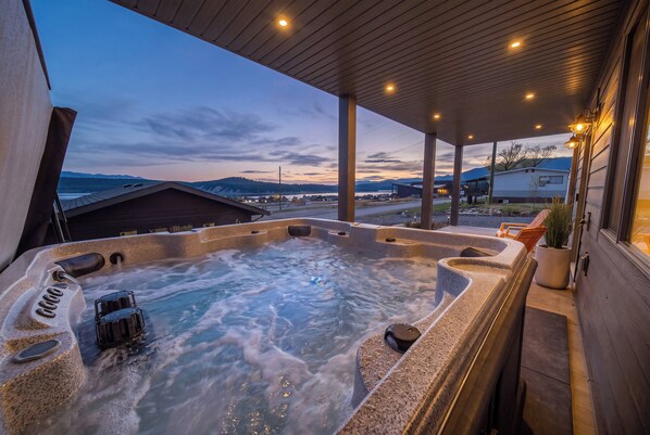A hot tub with a view of a town and mountains in the background.